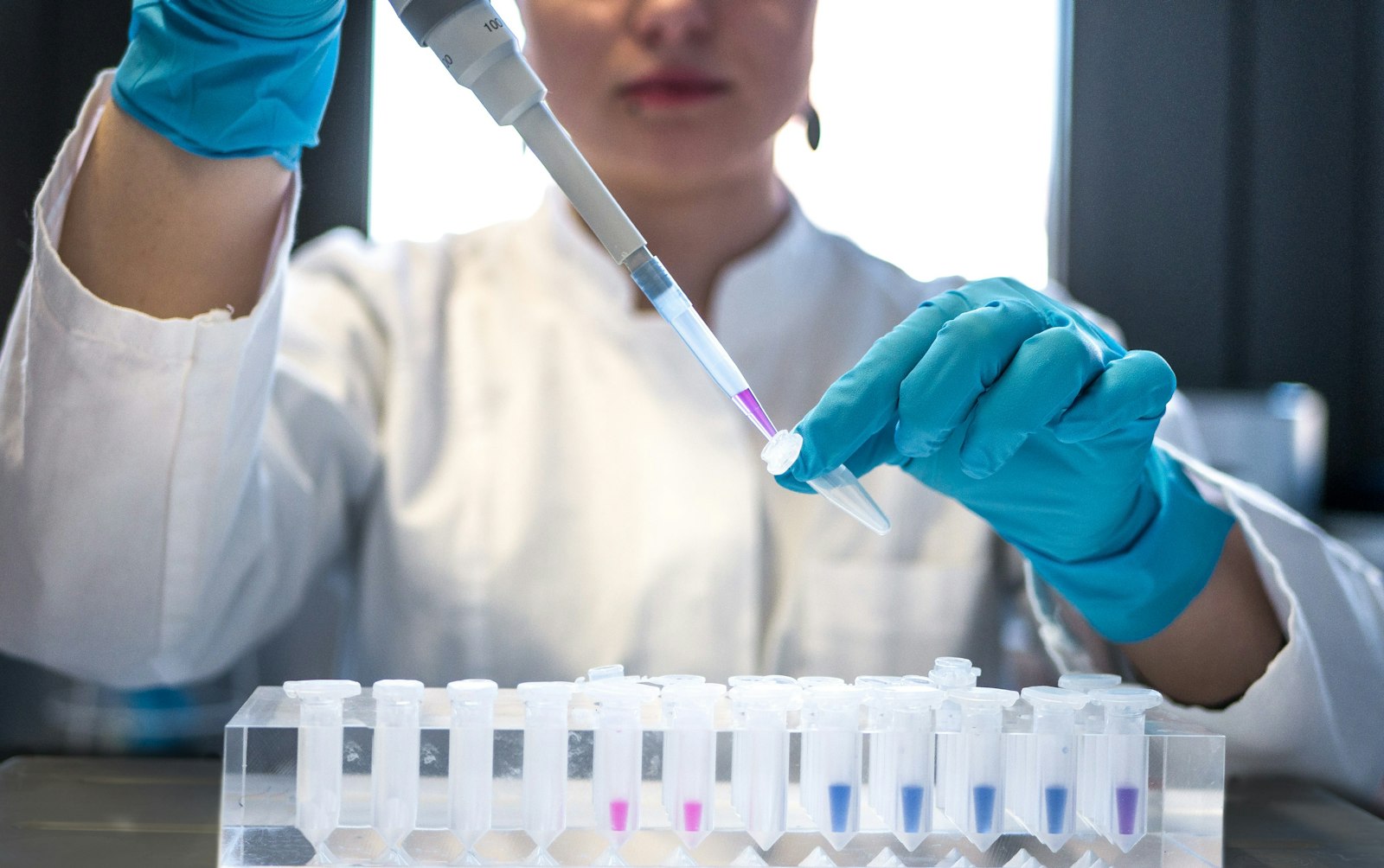 Scientist pipetting samples into test tubes in a research lab