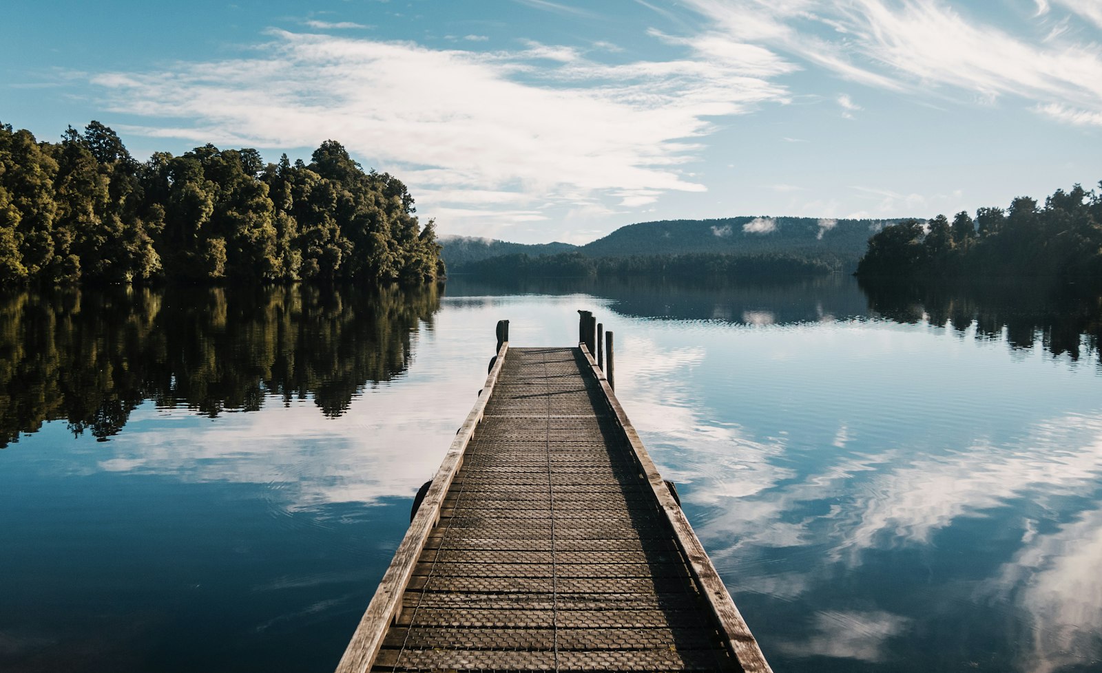 Wooden jetty on a calm lake reflecting the sky