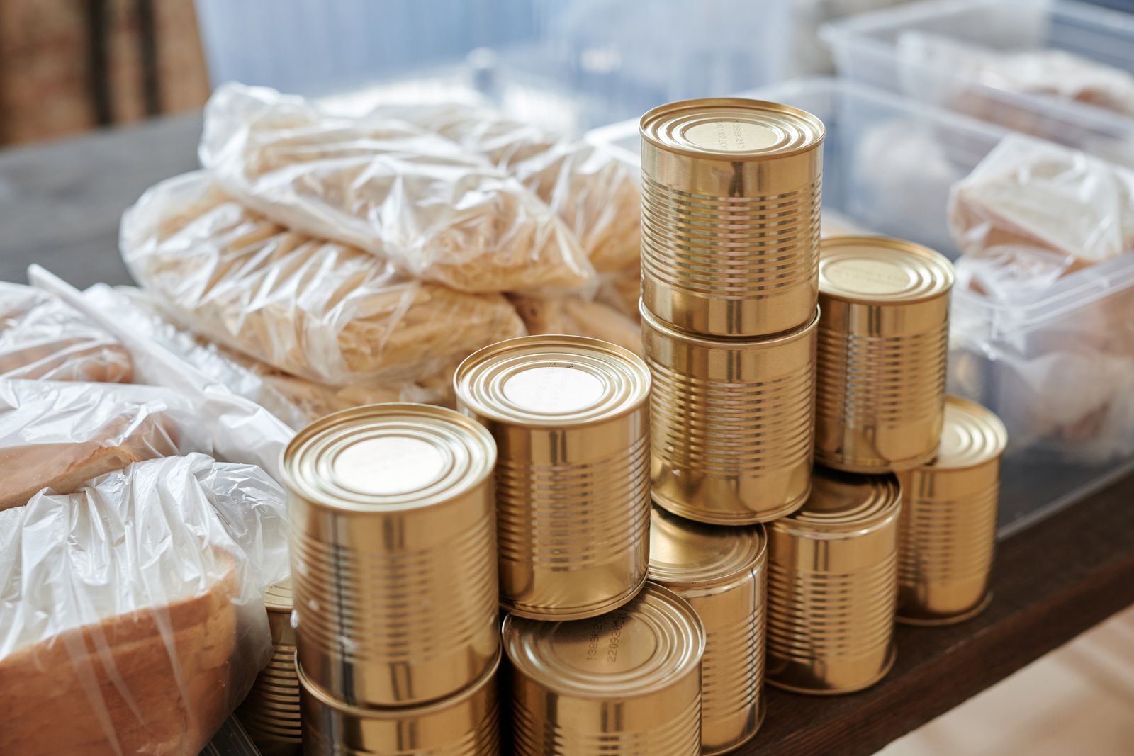 Stacks of unlabelled tins beside bags of pasta and bread on a table Stacks of unlabelled tins beside bags of pasta and bread on a table
