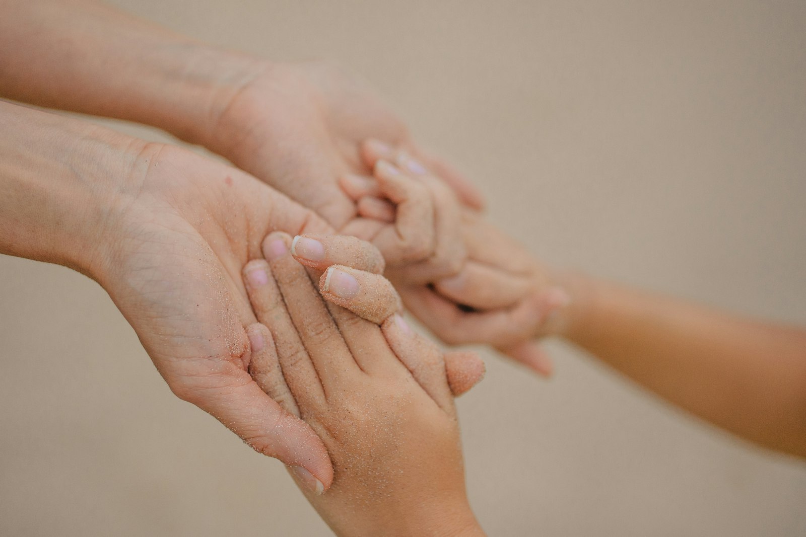 Adult hands gently holding a child's hands