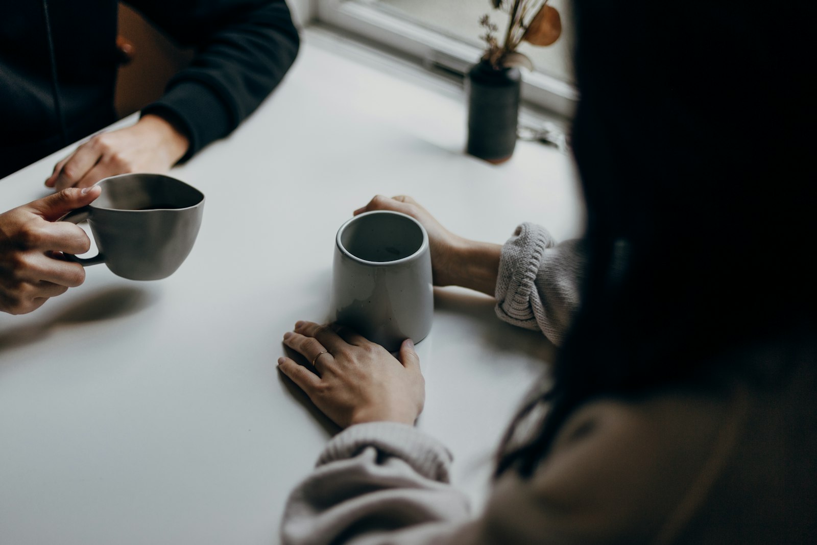 Two people talking over mugs at a table