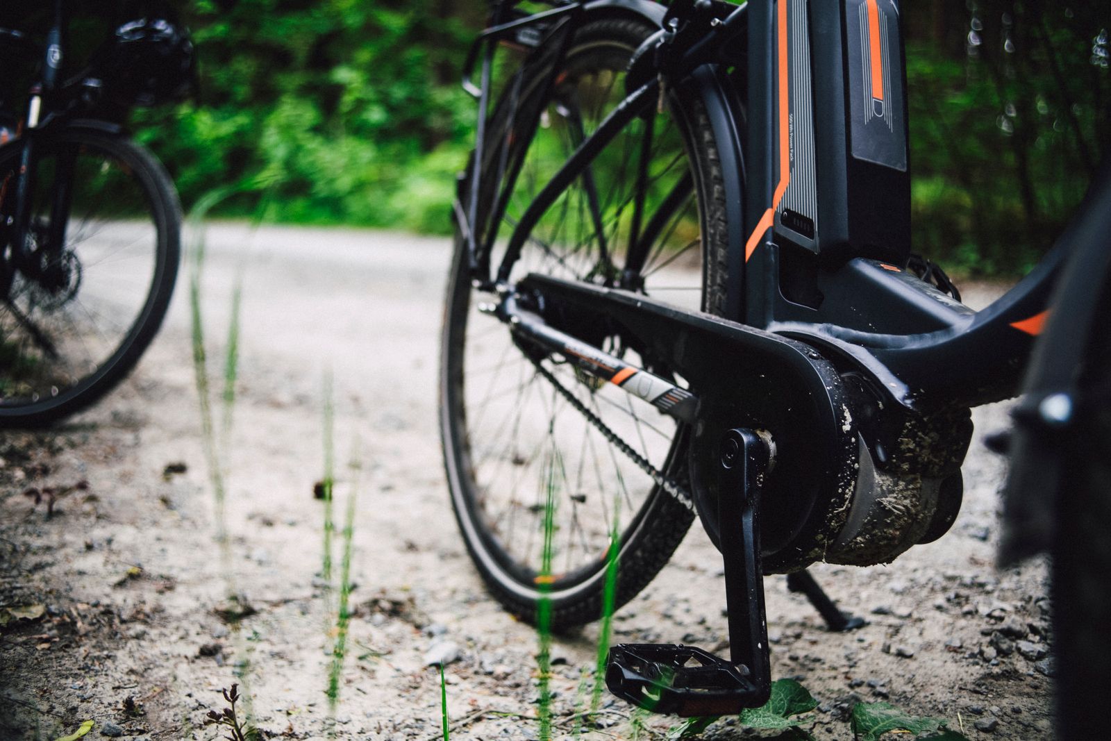 Close-up of an electric bike's pedal and motor on a gravel forest path