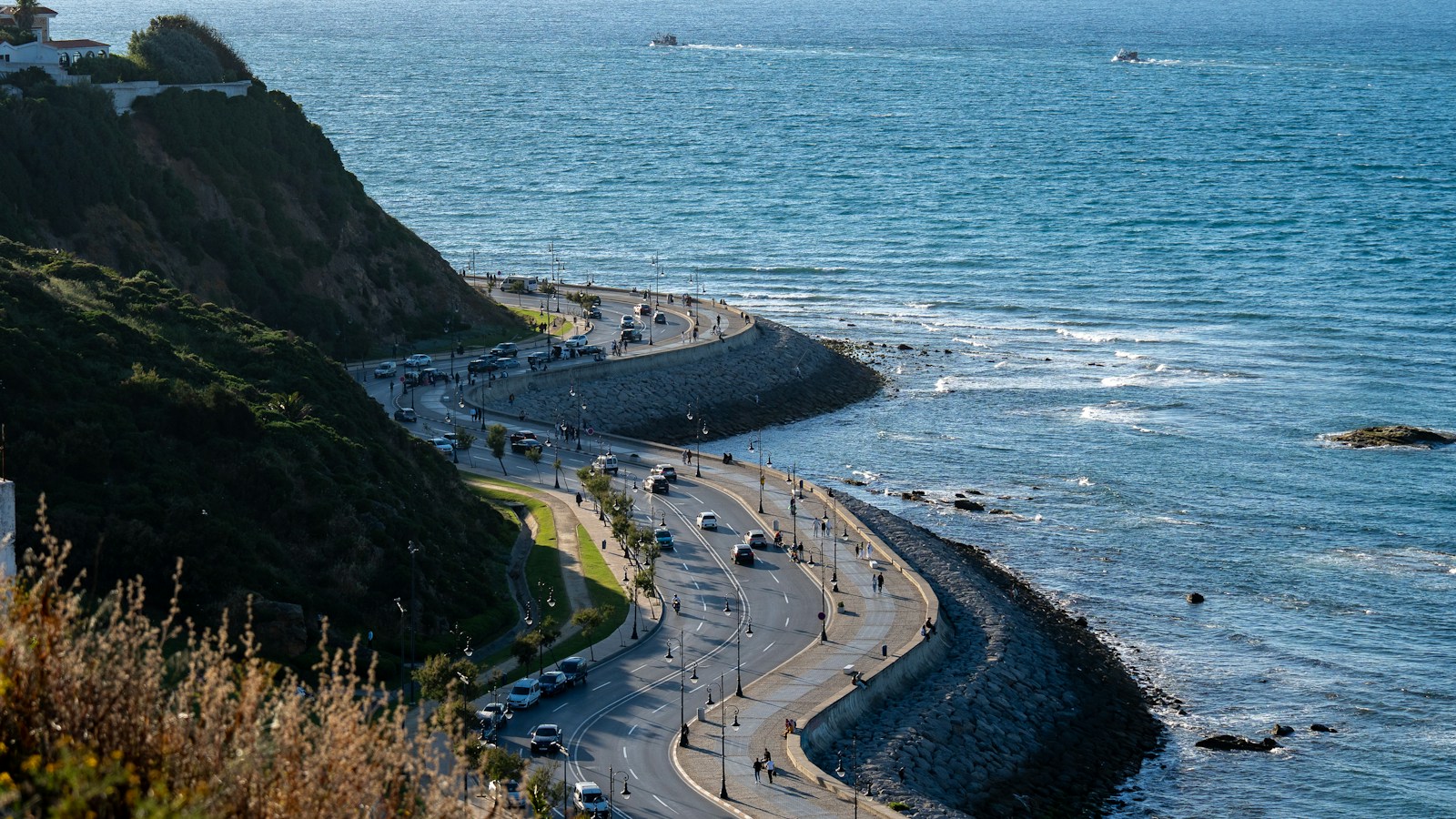 A coastal road curving along cliffs beside a blue sea