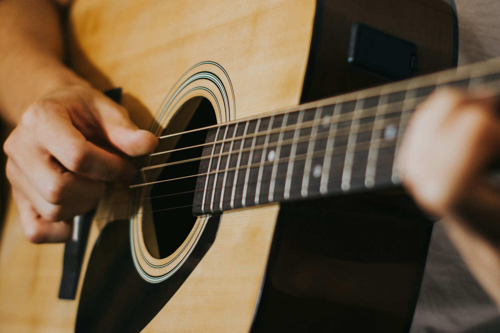 Close-up of hands strumming an acoustic guitar