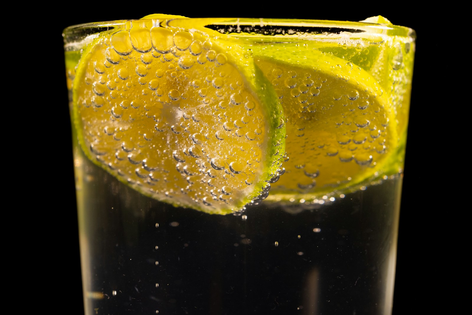 Close-up of lemon slices in a glass of sparkling water against a dark background