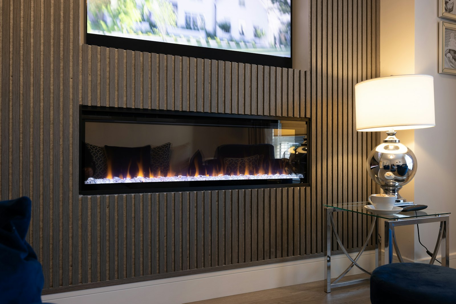 A living room with slatted wall panelling around an inset fire and white skirting along the floor