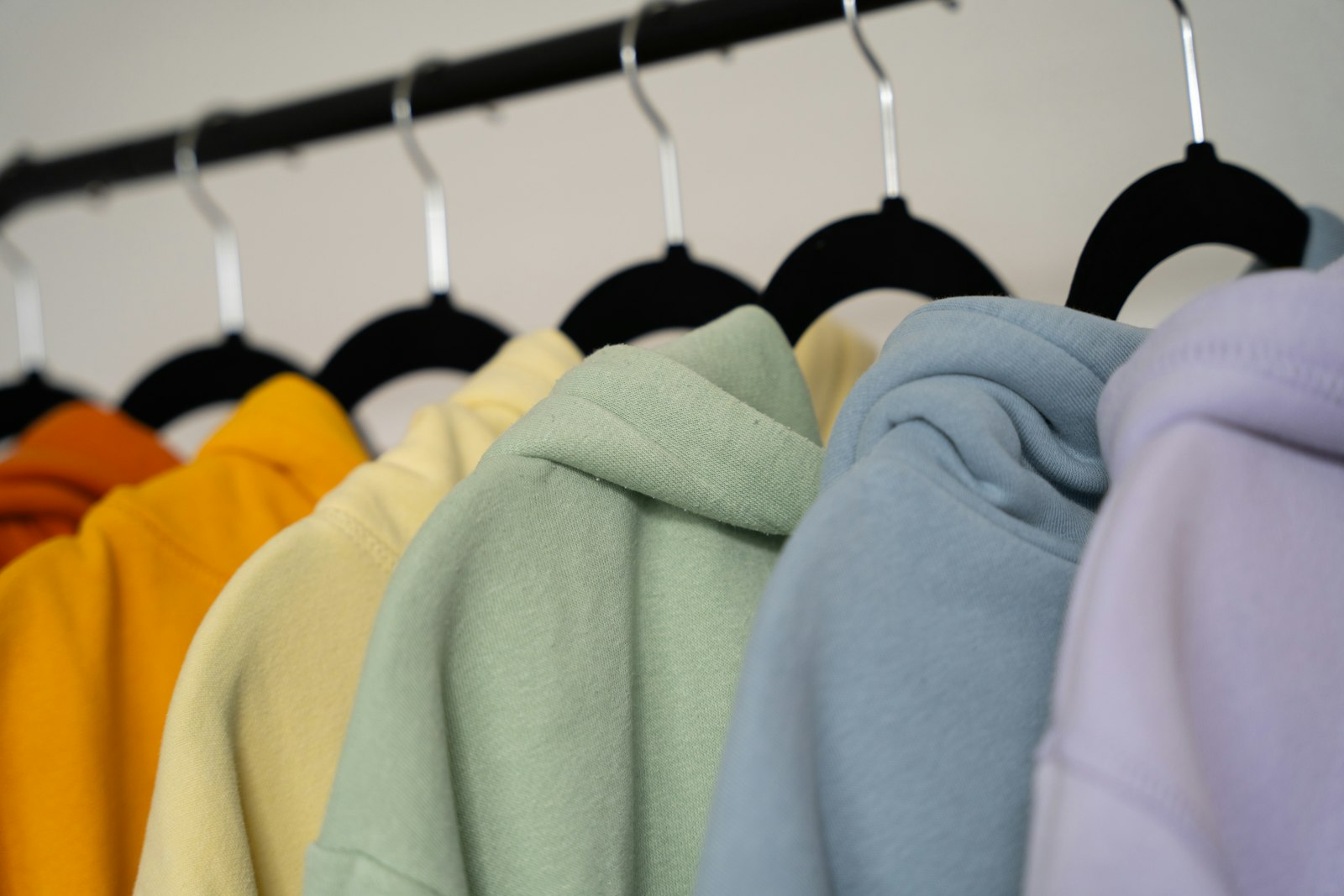 Row of pastel-coloured hoodies hanging on a black clothes rail