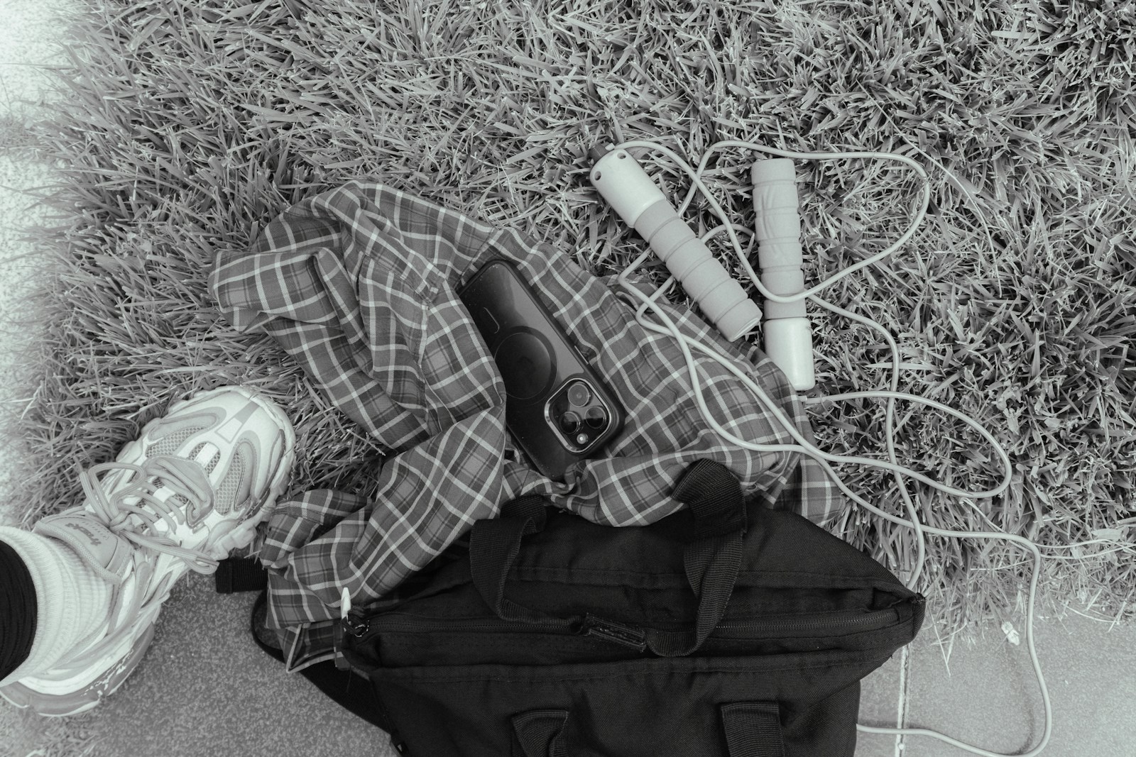 Workout gear including a skipping rope, gym bag and trainers laid out on grass
