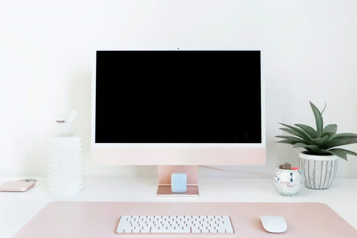 A desktop computer with a keyboard and mouse on a tidy white desk beside a potted plant A desktop computer with a keyboard and mouse on a tidy white desk beside a potted plant
