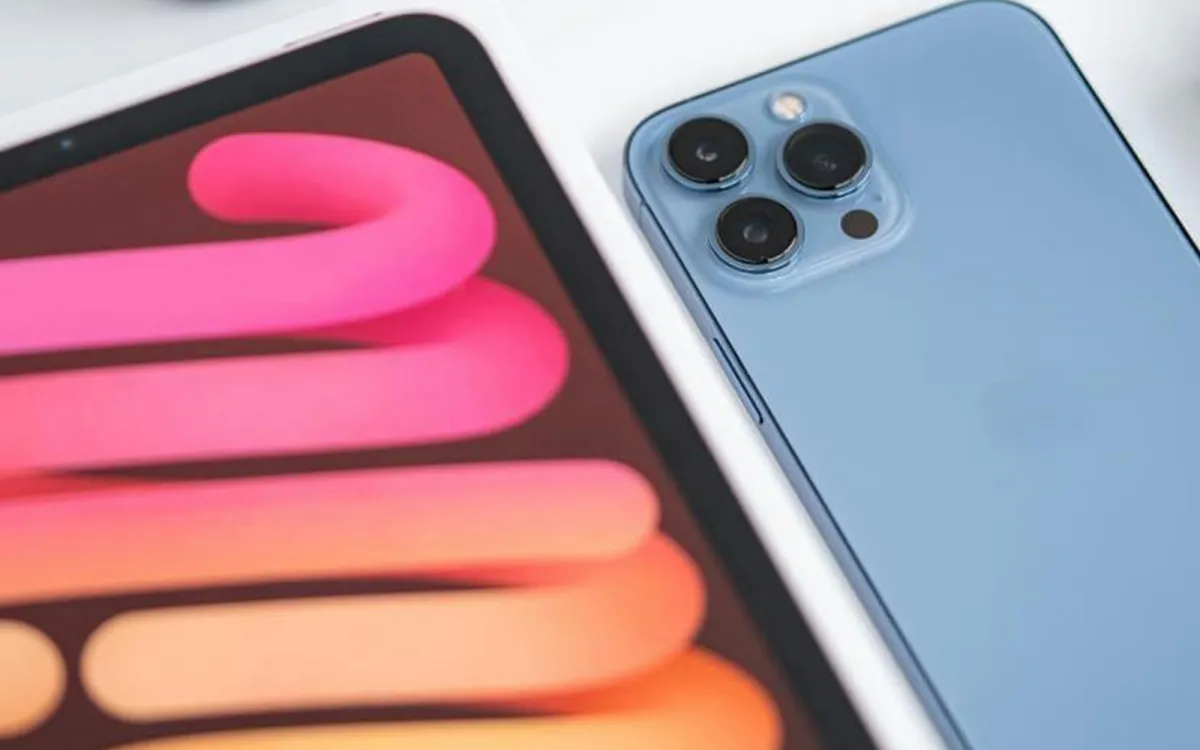 A light blue smartphone lying next to a tablet on a white table A light blue smartphone lying next to a tablet on a white table