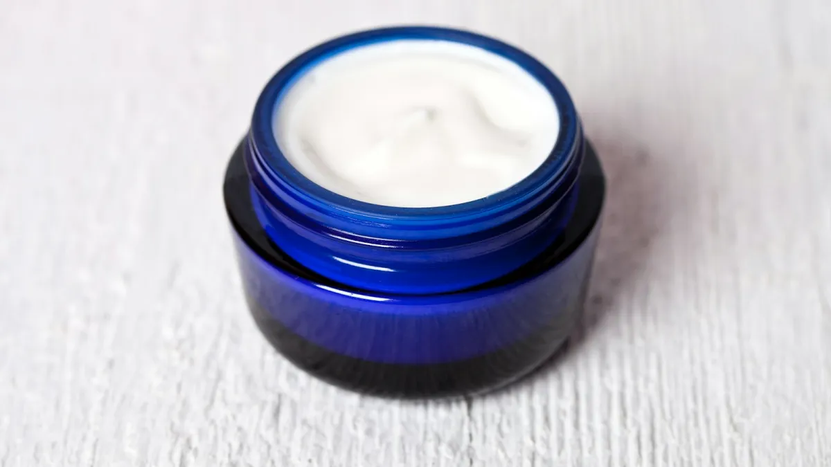 Open blue glass jar of white cream on a pale wooden surface Open blue glass jar of white cream on a pale wooden surface