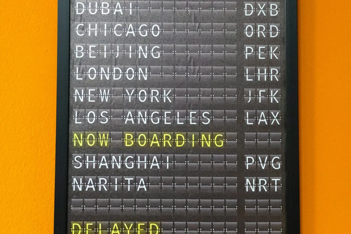 A split-flap departures board listing world cities with a delayed flight