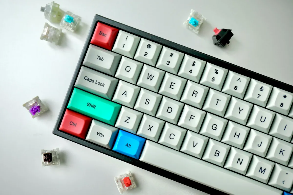 A mechanical keyboard with white, red, green and blue keycaps surrounded by loose key switches