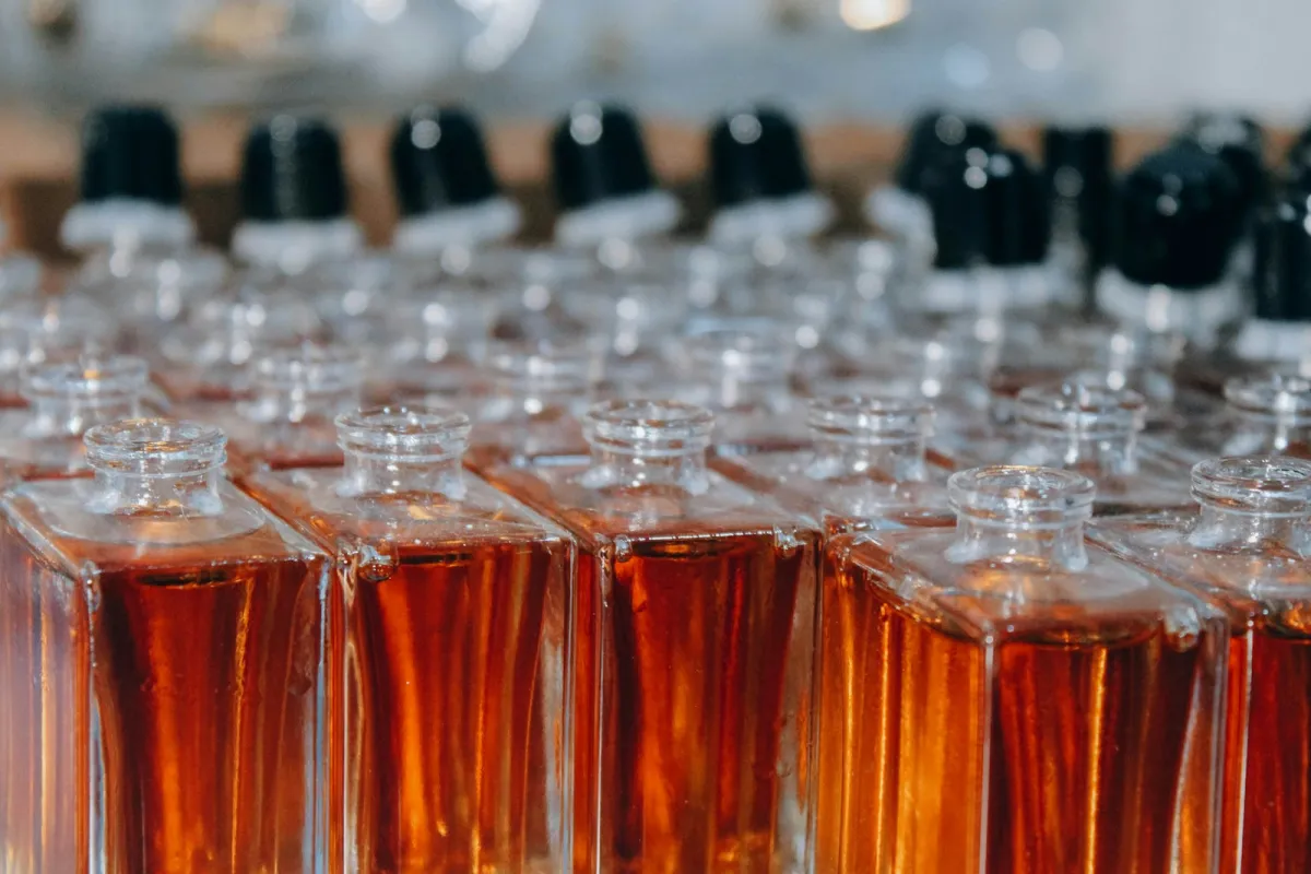 Rows of glass perfume bottles filled with amber liquid