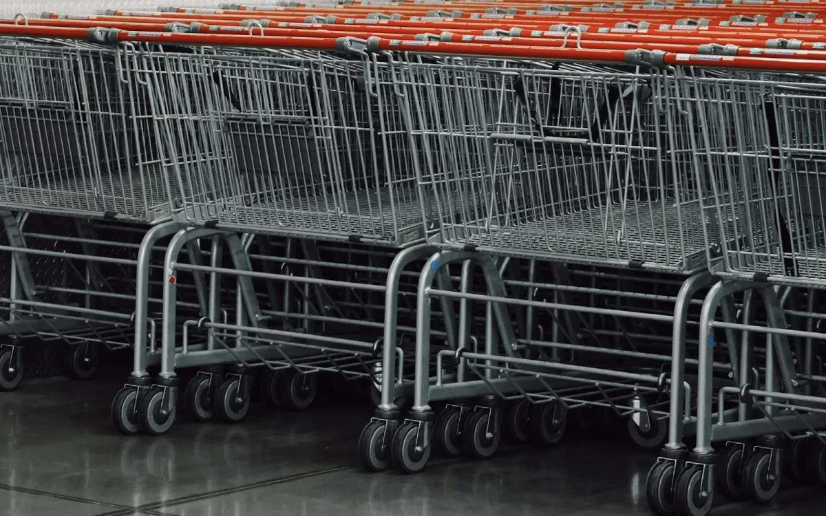 A row of empty supermarket trolleys lined up on a shiny shop floor A row of empty supermarket trolleys lined up on a shiny shop floor