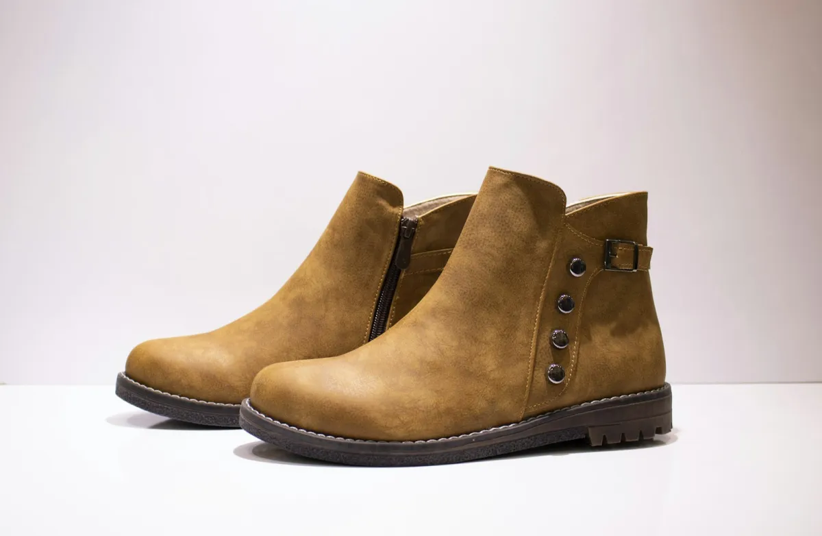 A pair of tan ankle boots on a white background A pair of tan ankle boots on a white background