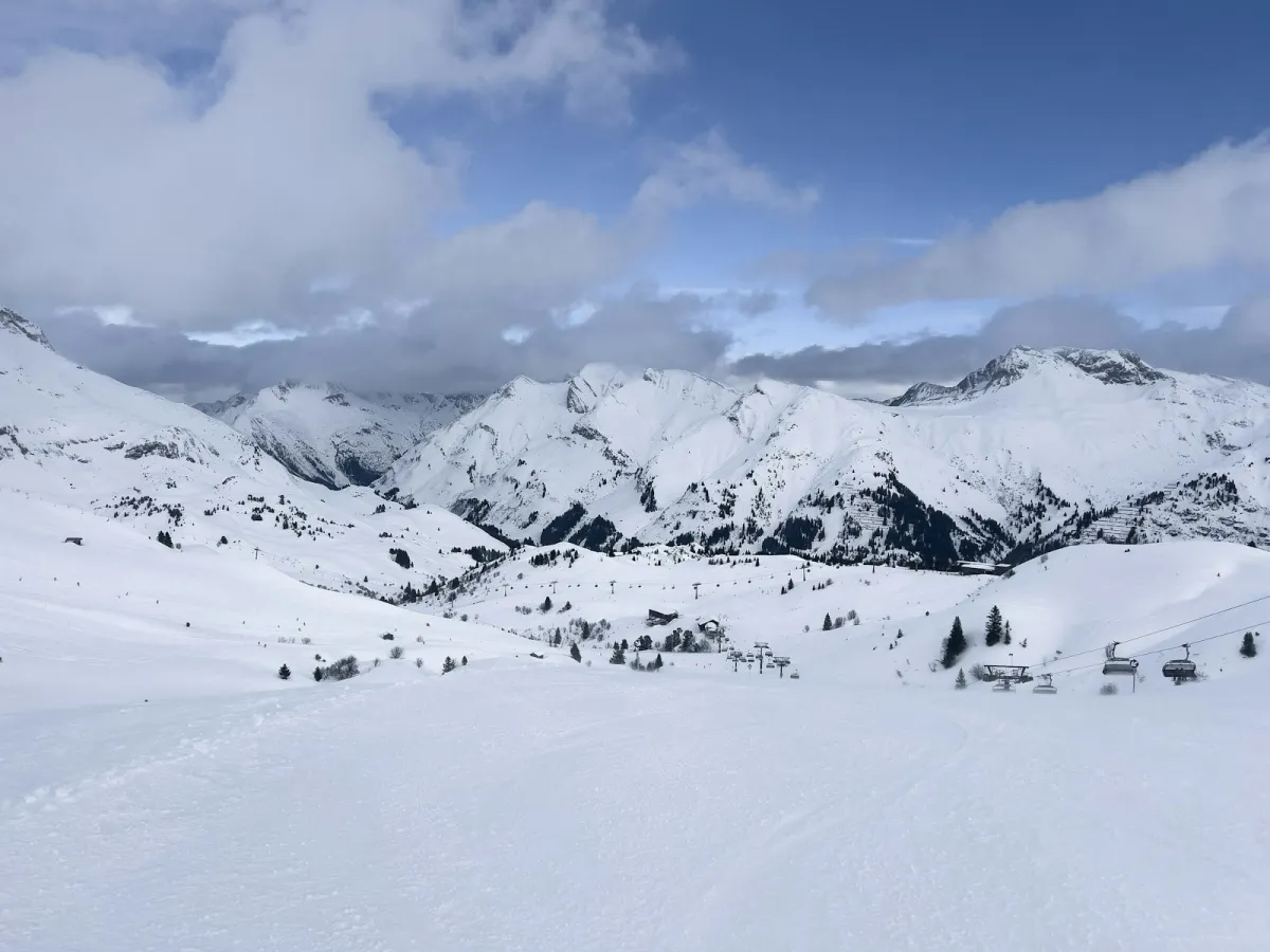 A snowy Austrian ski resort seen from above with the Alps behind