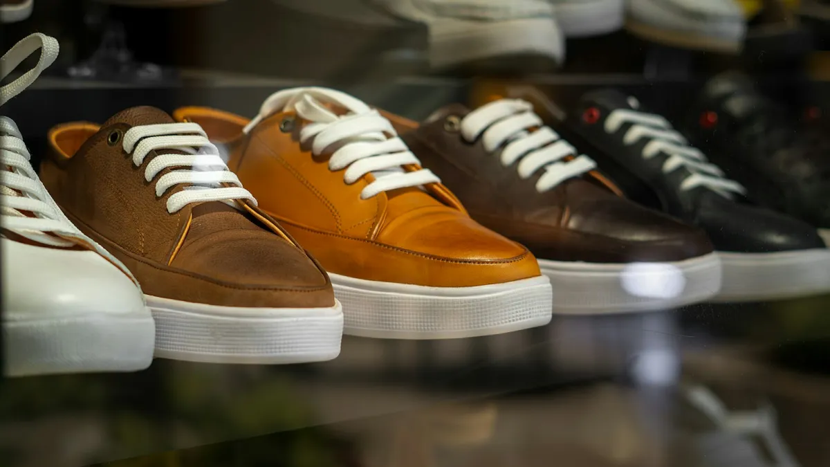 A row of leather trainers with white soles and laces on a shop display shelf