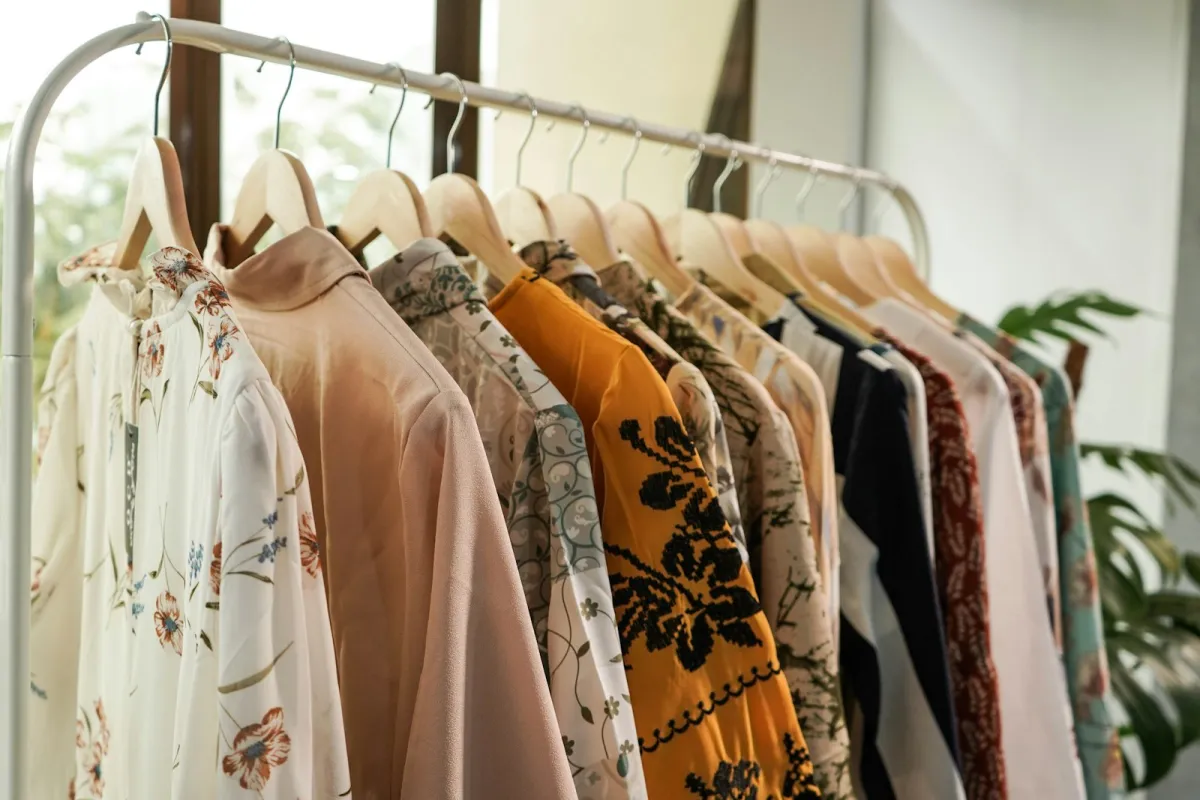 A row of patterned blouses on wooden hangers on a clothing rail A row of patterned blouses on wooden hangers on a clothing rail