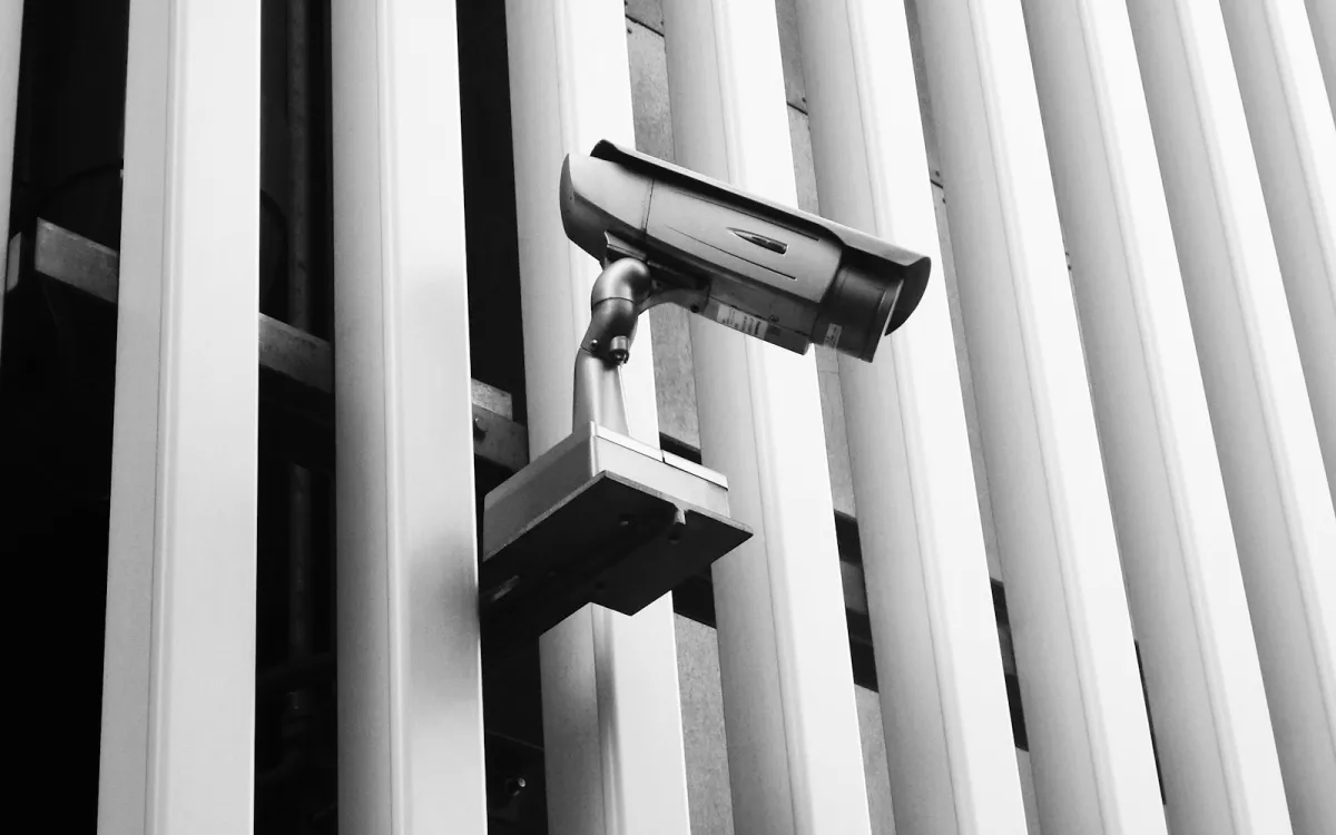 Black and white photo of a security camera mounted on the side of a building