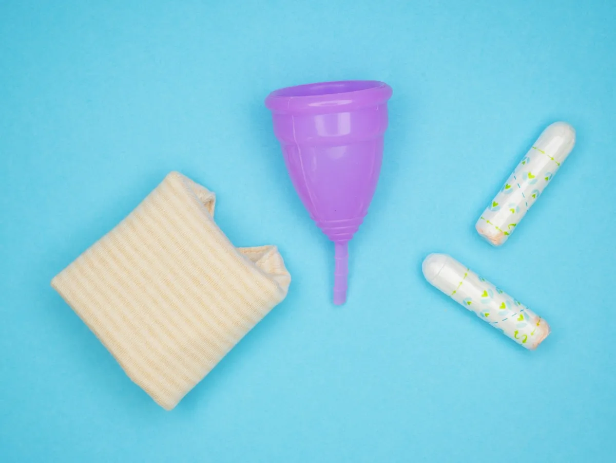 A purple menstrual cup, folded cotton underwear and two tampons on a blue background A purple menstrual cup, folded cotton underwear and two tampons on a blue background