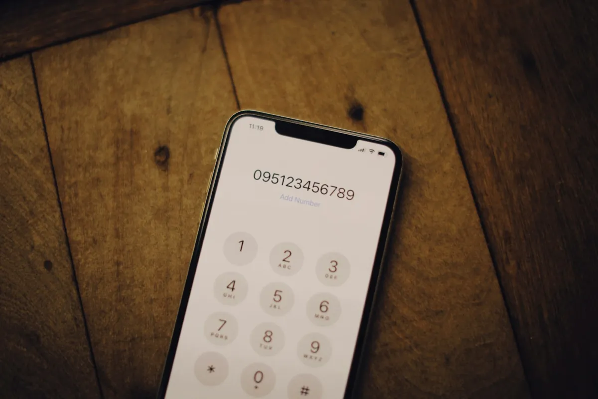 Smartphone showing a phone keypad lying on a wooden table