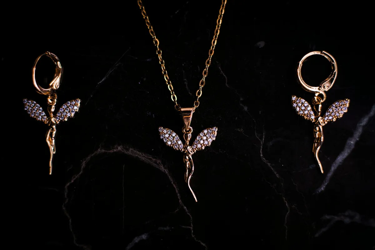 A gold pendant necklace and matching drop earrings on dark marble A gold pendant necklace and matching drop earrings on dark marble