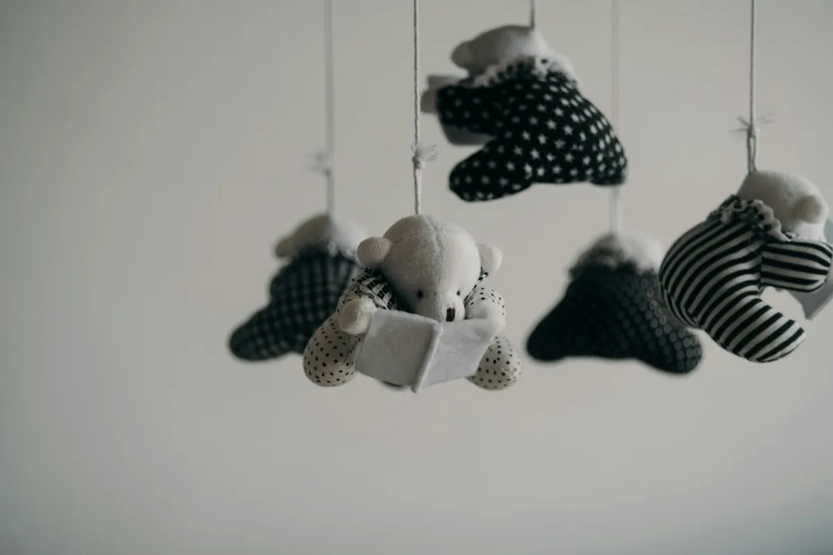 A black-and-white fabric cot mobile with a teddy bear reading a book A black-and-white fabric cot mobile with a teddy bear reading a book
