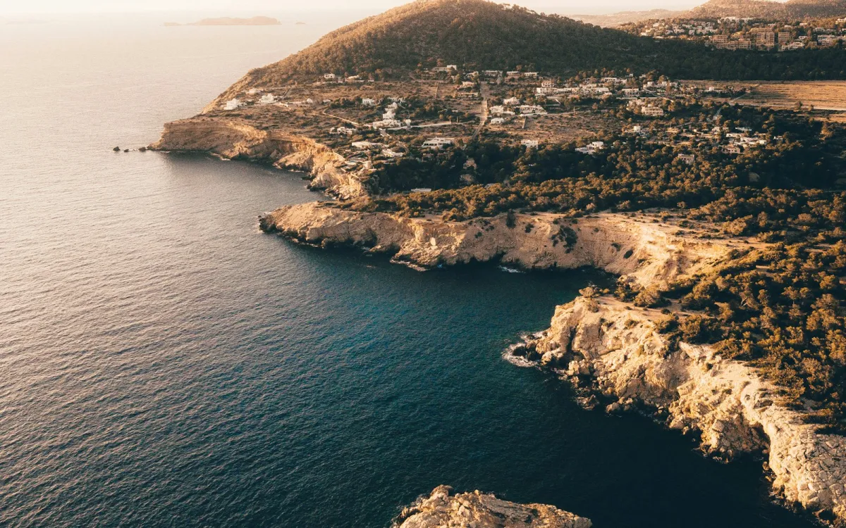 Aerial view of rocky cliffs and a deep blue cove on the Ibiza coastline at sunset Aerial view of rocky cliffs and a deep blue cove on the Ibiza coastline at sunset