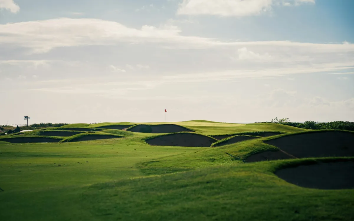 Rolling green golf course with sand bunkers and a red flag on the distant green Rolling green golf course with sand bunkers and a red flag on the distant green