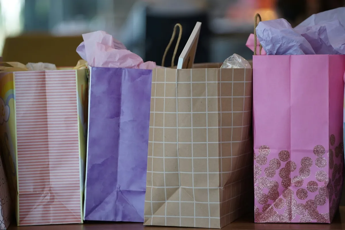 Colourful paper gift bags with tissue paper lined up on a table