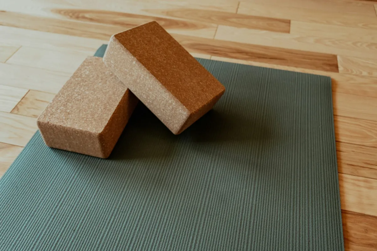 Green yoga mat with two cork blocks on a wooden floor