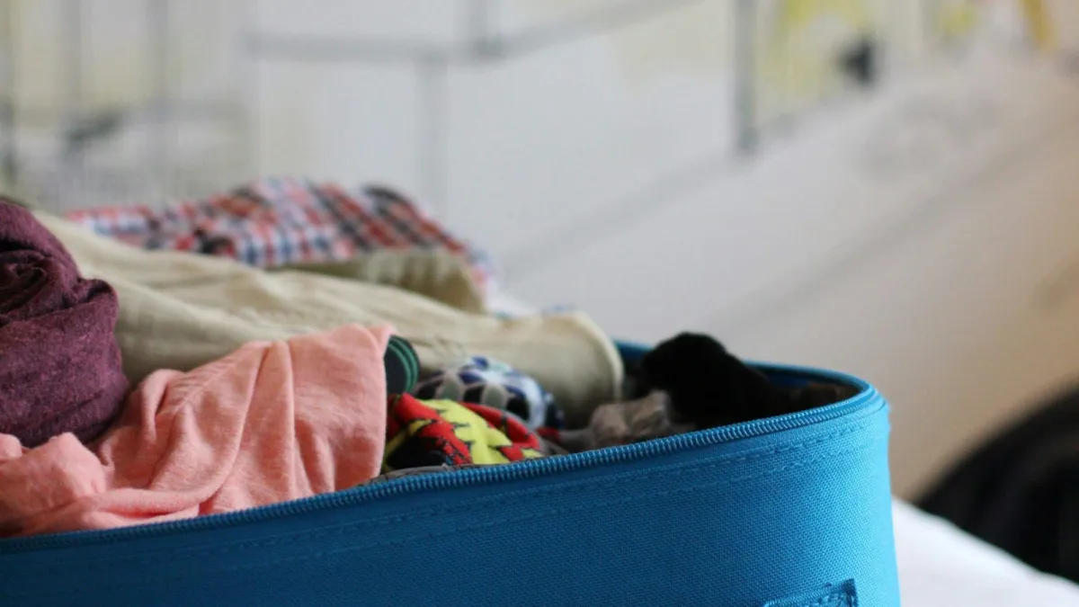 Blue soft suitcase packed with folded clothes