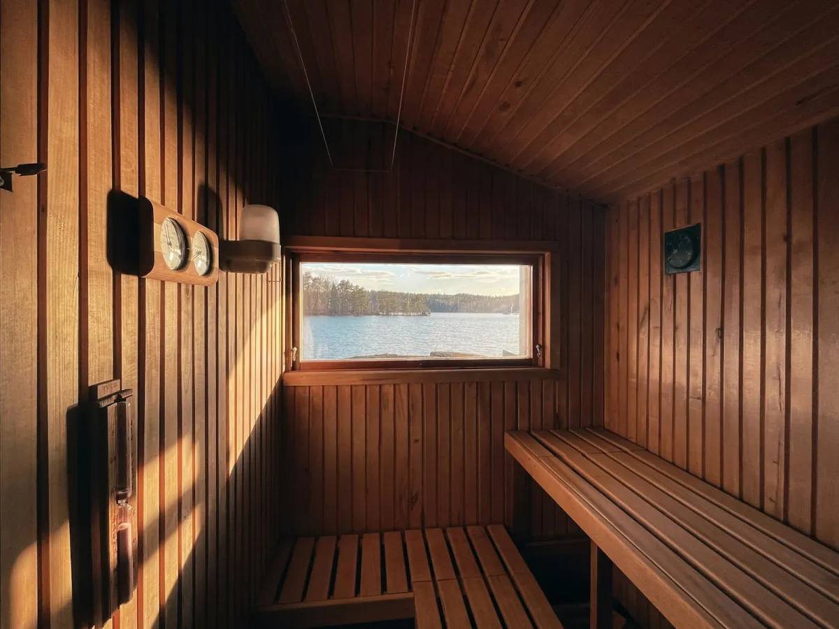 Inside a wooden sauna with slatted benches and a window looking out over a lake Inside a wooden sauna with slatted benches and a window looking out over a lake