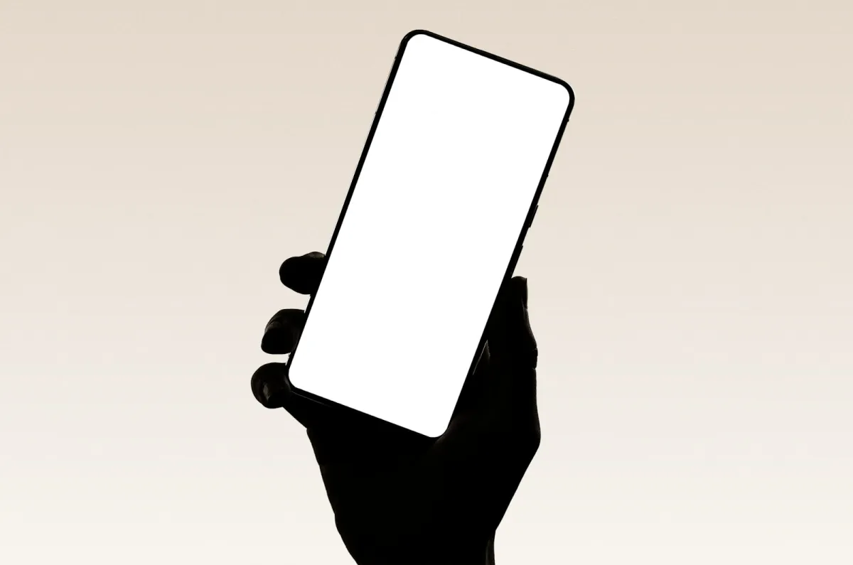 Silhouette of a hand holding up a smartphone with a blank white screen Silhouette of a hand holding up a smartphone with a blank white screen