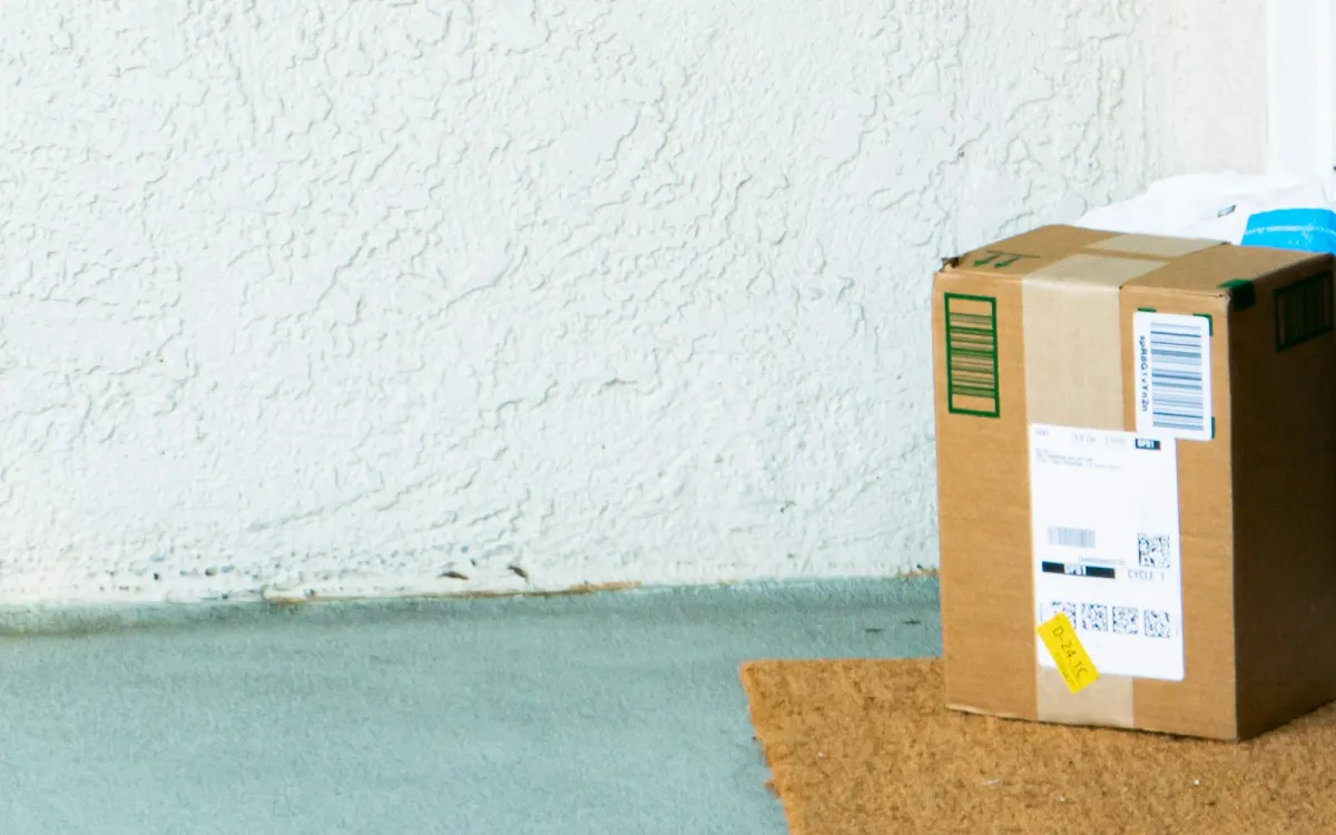 A cardboard parcel left on a doormat outside a front door A cardboard parcel left on a doormat outside a front door