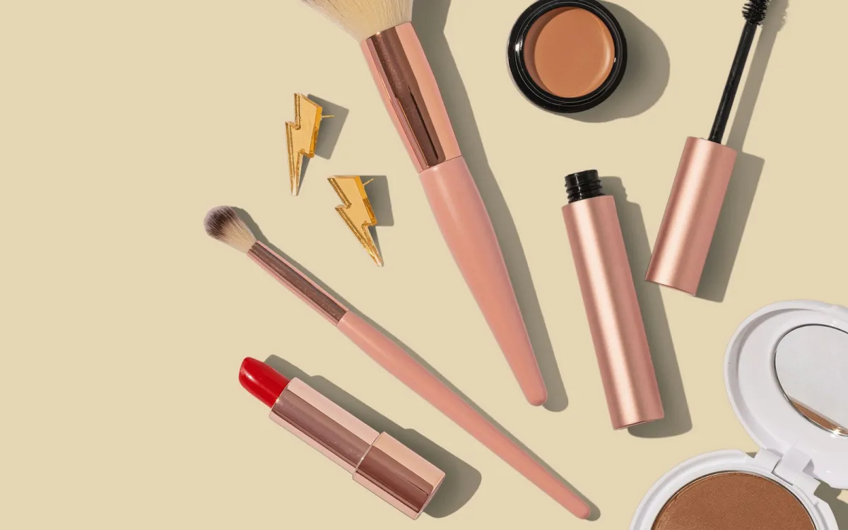 Make-up brushes, a red lipstick, mascara and powder compacts laid out on a cream background Make-up brushes, a red lipstick, mascara and powder compacts laid out on a cream background