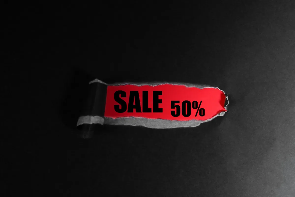 A red 'Sale 50%' label revealed through torn black paper