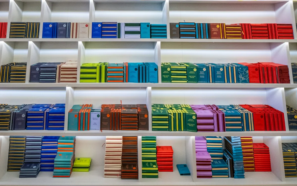 Rows of colourful books arranged by colour on white shelves Rows of colourful books arranged by colour on white shelves