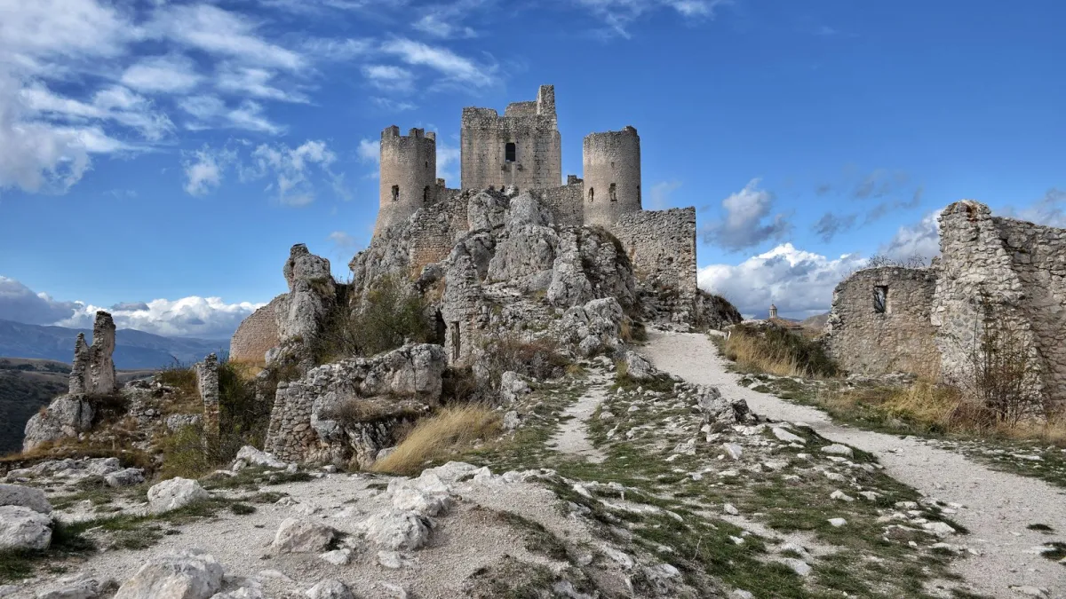 The stone ruins of Rocca Calascio castle on a rocky hilltop in Abruzzo under a blue sky The stone ruins of Rocca Calascio castle on a rocky hilltop in Abruzzo under a blue sky