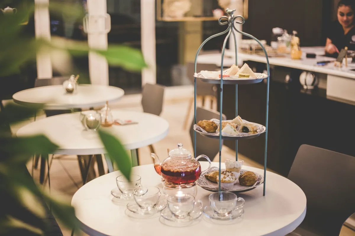 Afternoon tea on a three-tier stand with a glass teapot and cups