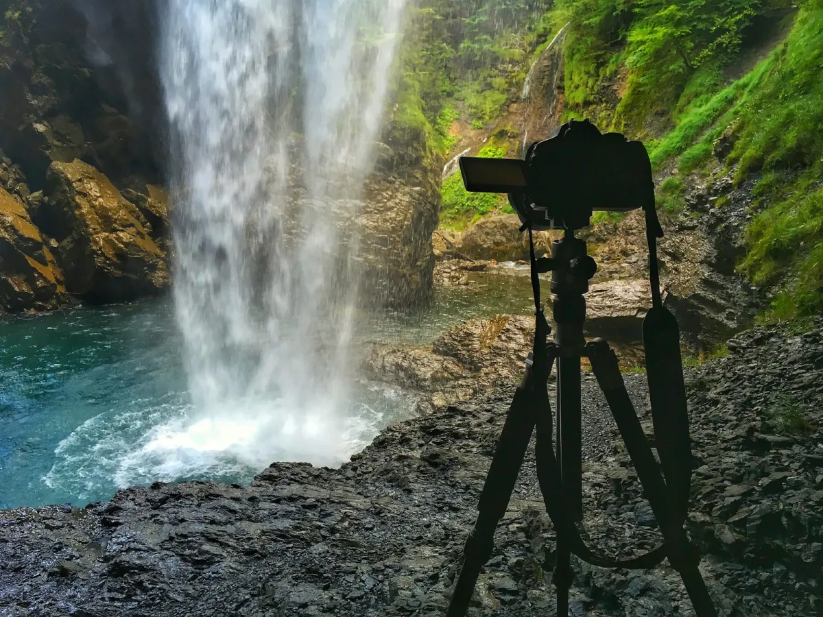 A camera on a tripod in front of a waterfall A camera on a tripod in front of a waterfall
