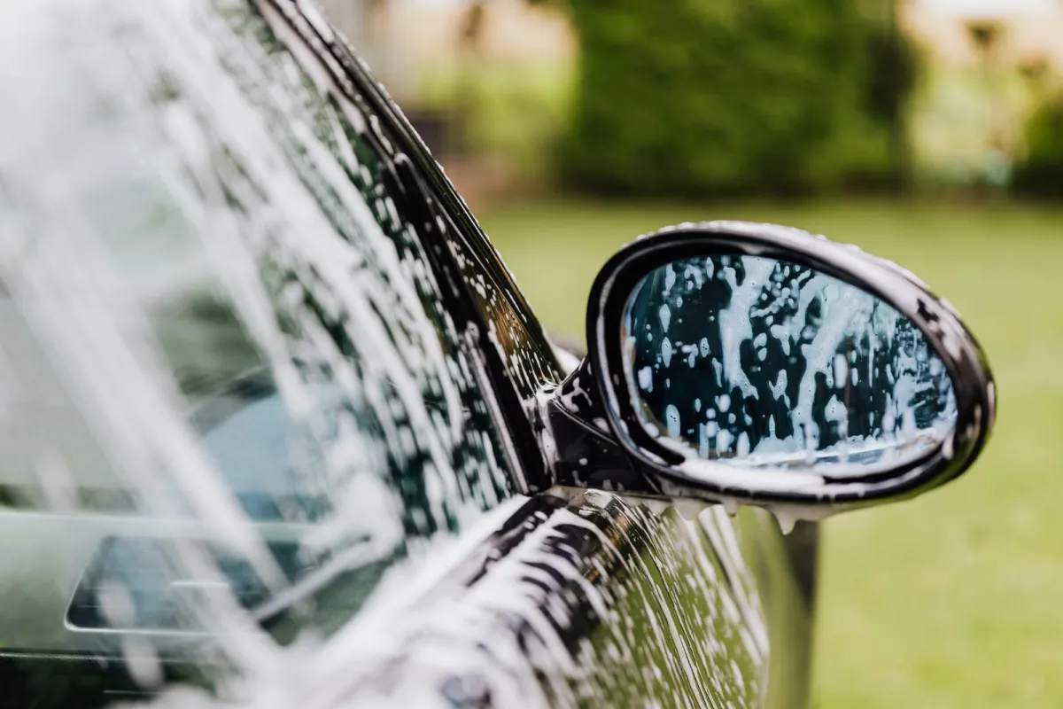 A car's wing mirror and window covered in soapy foam during a wash A car's wing mirror and window covered in soapy foam during a wash