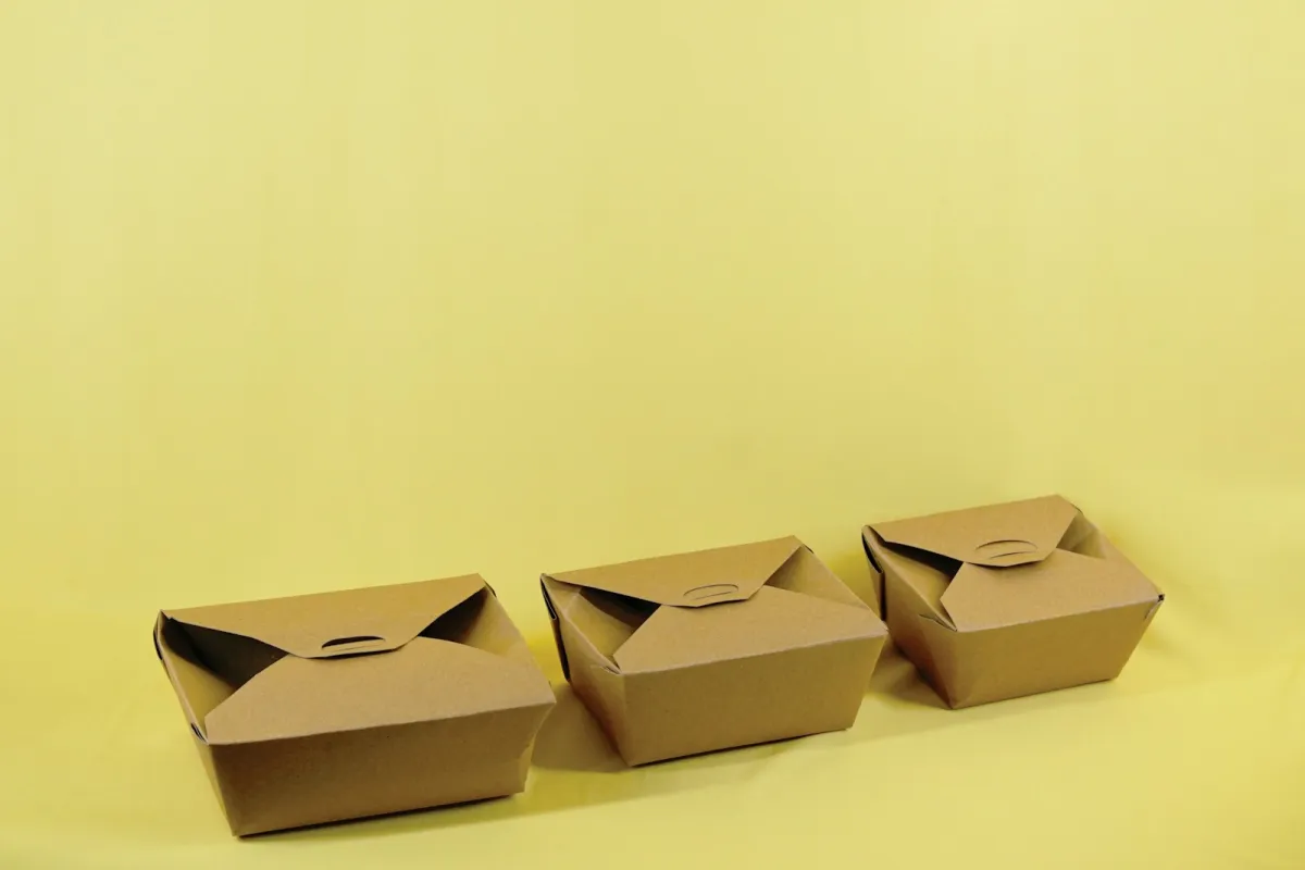Three plain brown cardboard boxes in different sizes on a yellow background Three plain brown cardboard boxes in different sizes on a yellow background