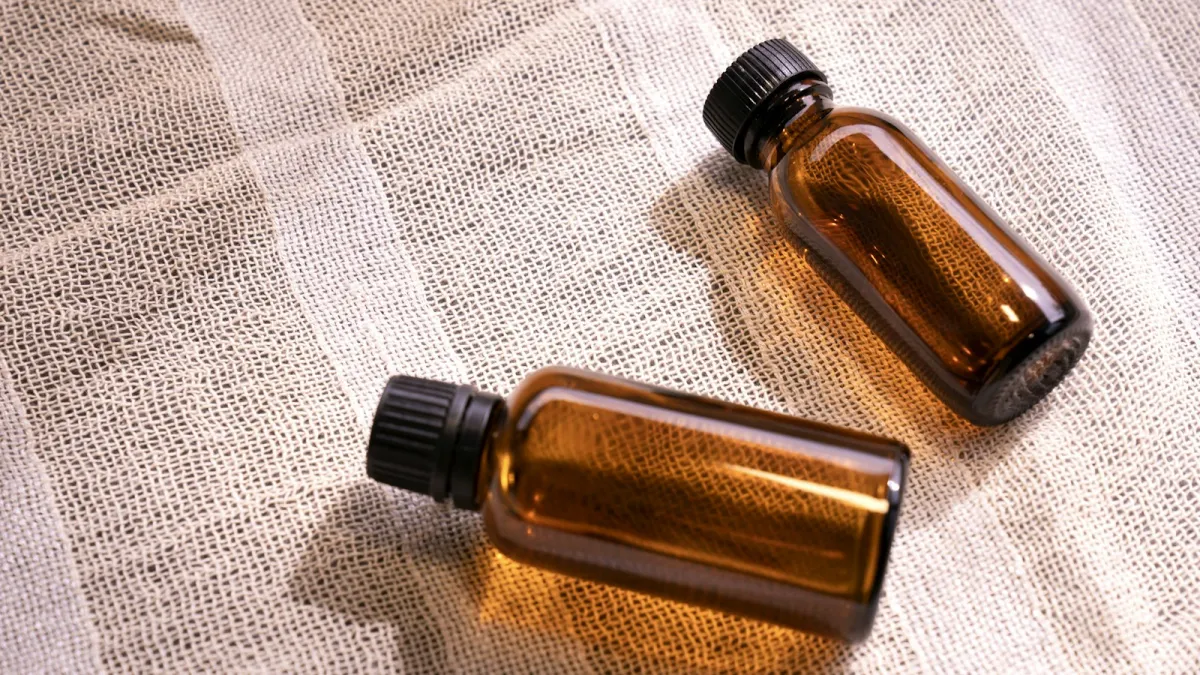 Two small amber glass bottles lying on loose-weave white cloth Two small amber glass bottles lying on loose-weave white cloth