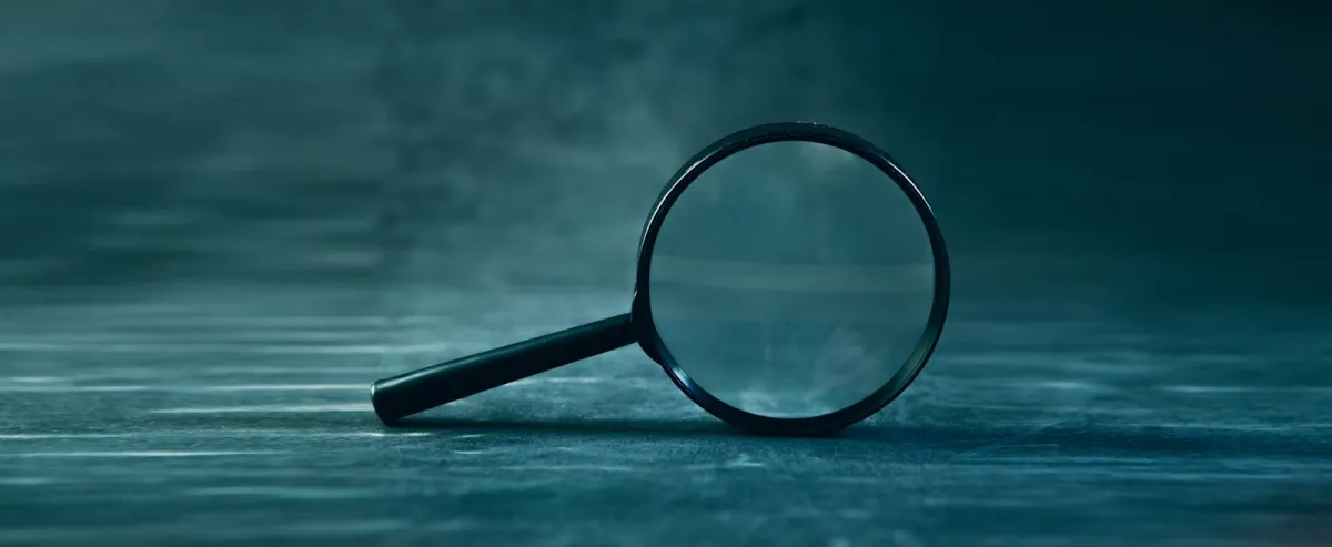 A magnifying glass resting on a dark blue-green surface A magnifying glass resting on a dark blue-green surface