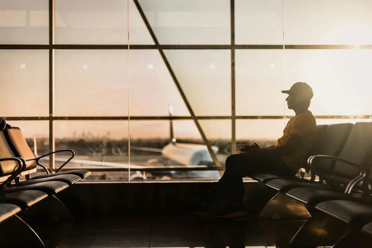 Silhouette of a traveller waiting in an airport departure lounge at sunset
