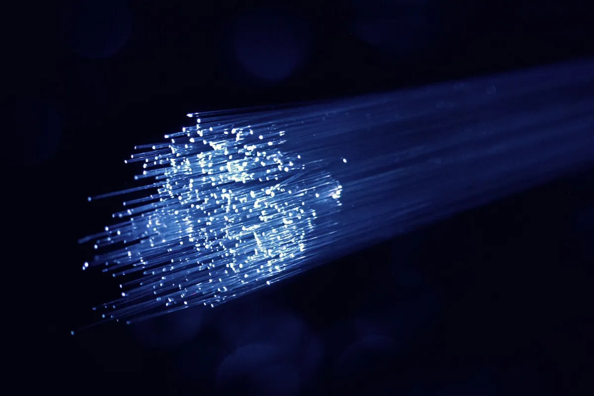 Strands of fibre optic cable glowing blue against a dark background Strands of fibre optic cable glowing blue against a dark background