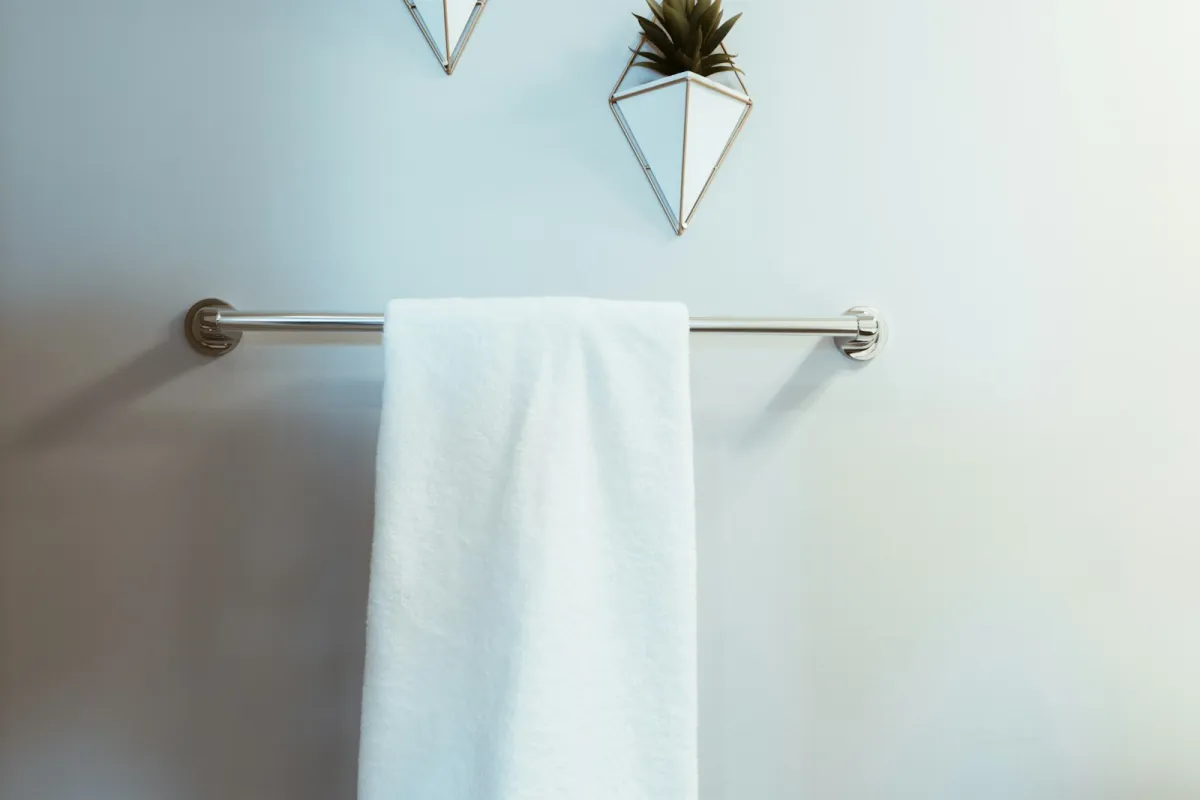 A white towel hanging on a chrome towel rail on a pale bathroom wall A white towel hanging on a chrome towel rail on a pale bathroom wall