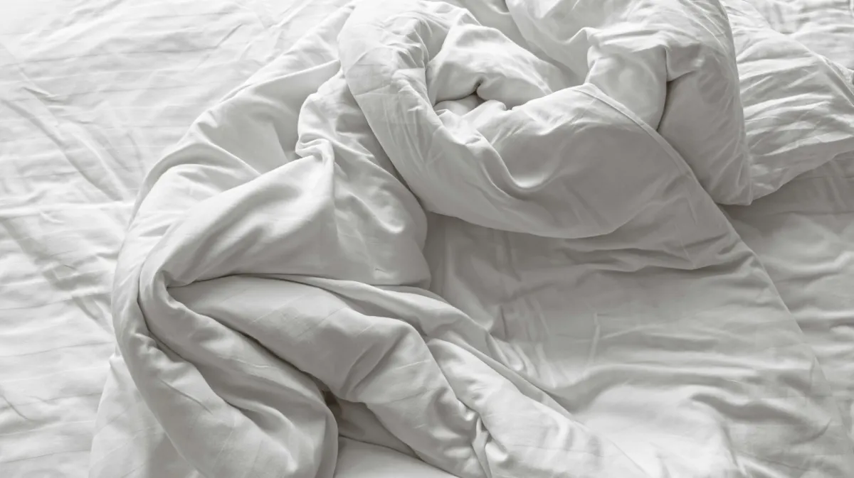 A rumpled white duvet and pillows on an unmade bed A rumpled white duvet and pillows on an unmade bed